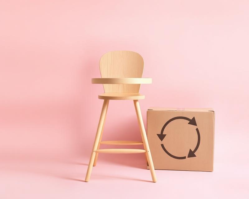 Chaise haute en bois et colis de retour sur fond rose