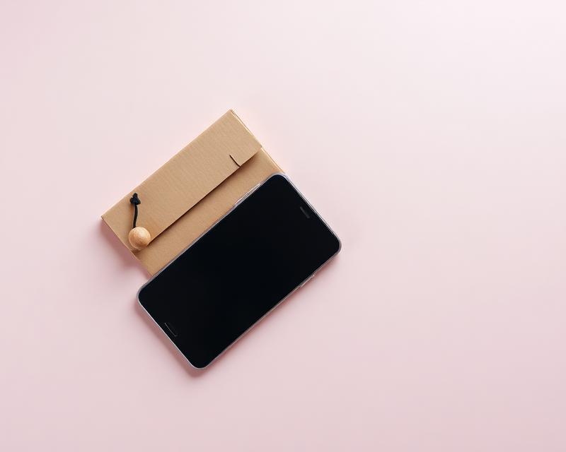 Smartphone et petit colis sur fond rose